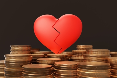 Broken red heart above stacks of coins representing the financial impact of a spouse spending marital money on an affair.